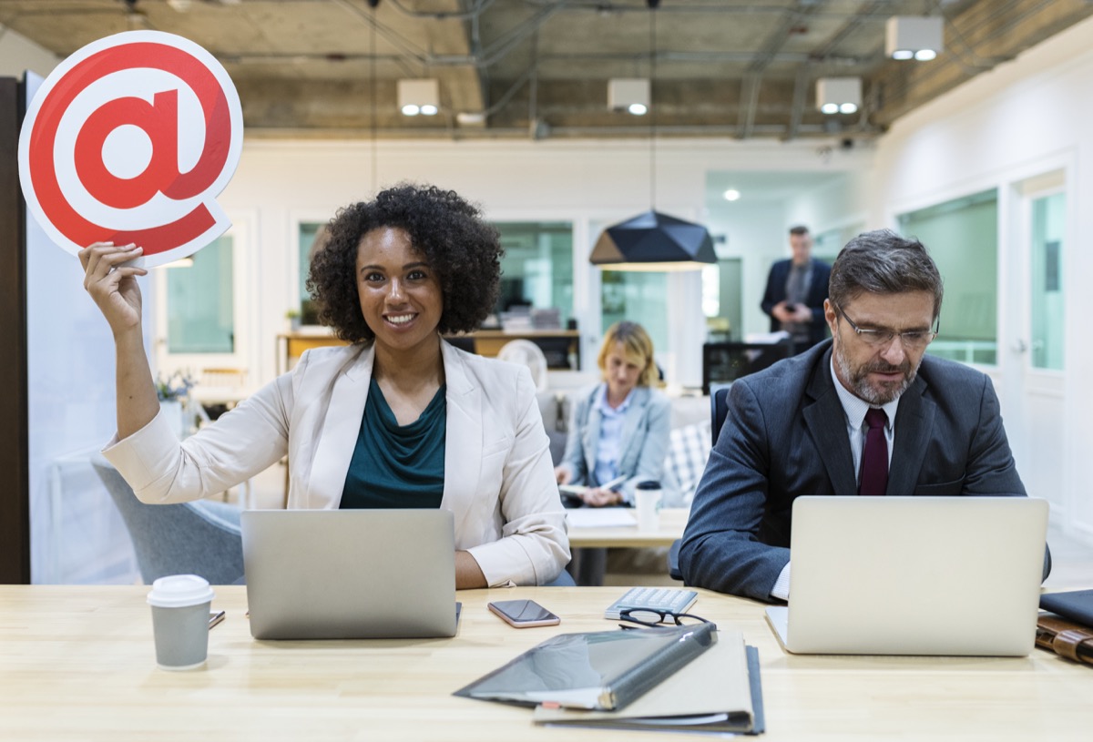 Businesswoman holding an @ sign in a South African office — email etiquette in the workplace